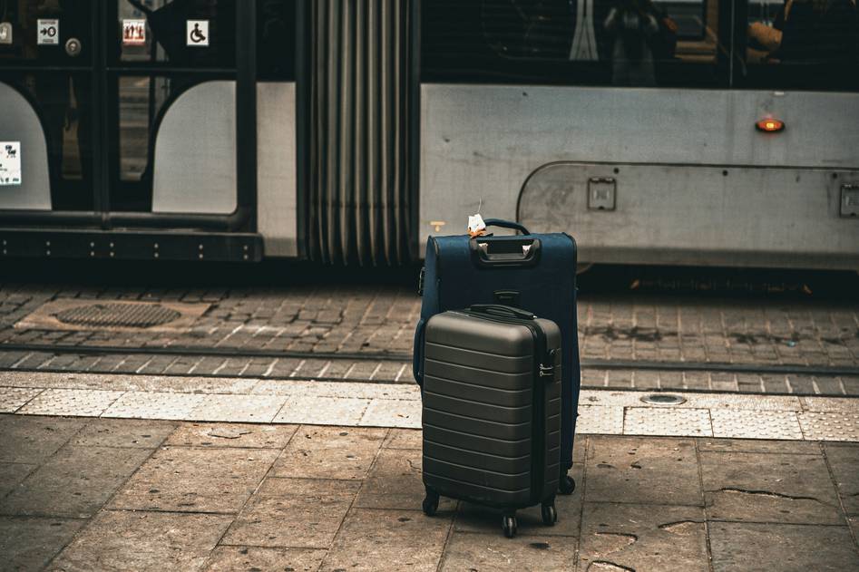 Traveler waiting at airport carousel with delayed luggage tag visible
