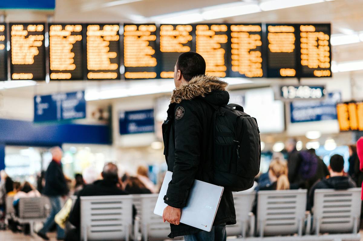 woman checking what is travel delay insurance on phone while waiting at airport
