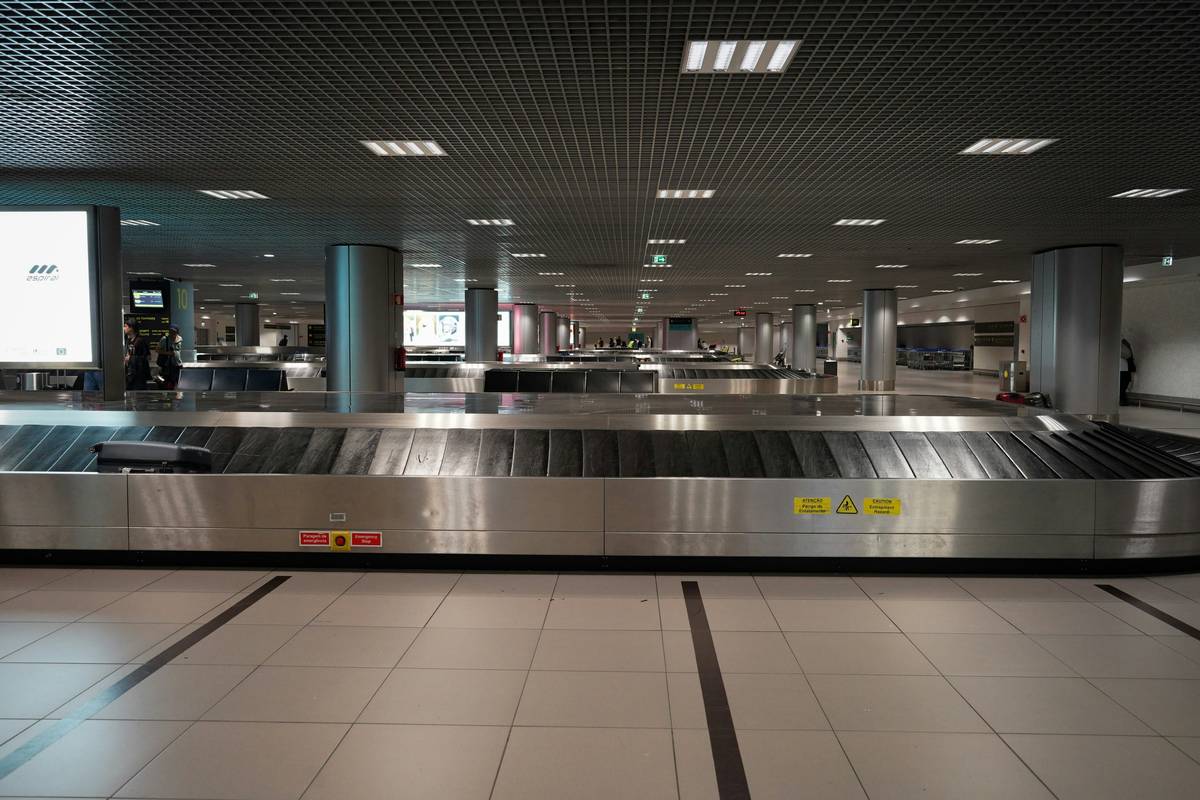 Traveler at airport baggage claim holding receipt for essentials purchased due to insurance for trip delay